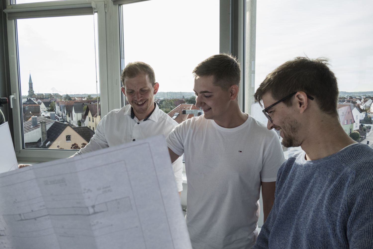 Drei Männer freuen sich beim Betrachten eines Architekturplans.